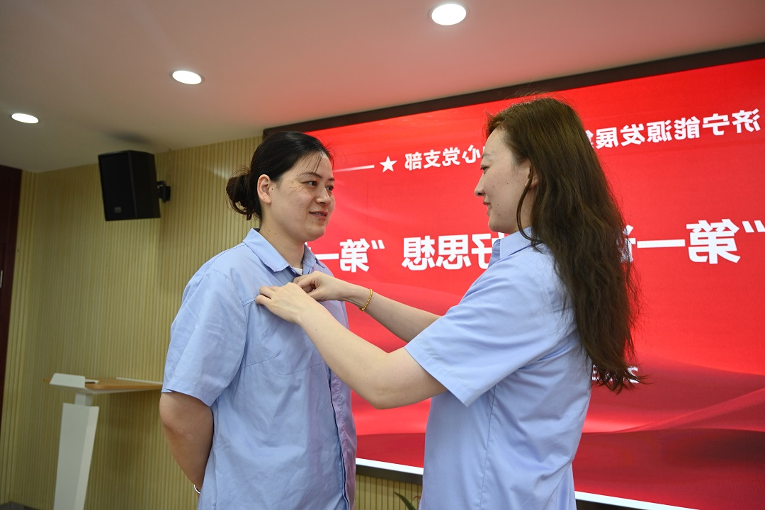 1697529443417408.jpg 2023年7月7日,老党员张旭为新党员戴党徽(地点:正则招标1112室,拍摄人:靳溢欣) - 网站.JPG